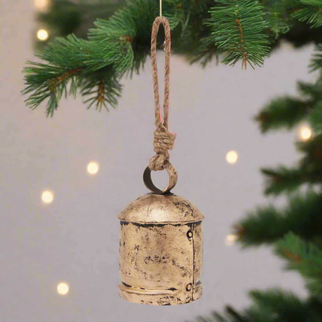 Antique Gold Bell Bauble hanging from a Christmas Tree, close up view.
