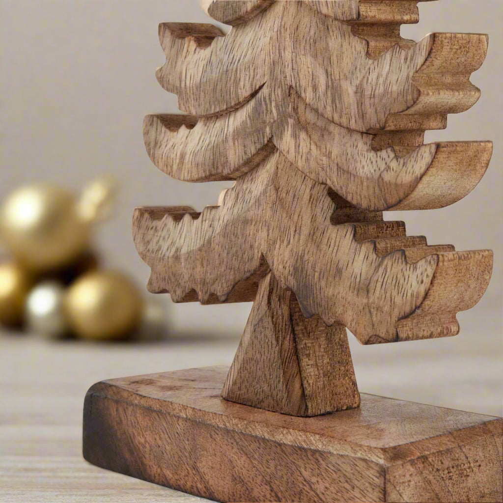 Close up view of bottom of wooden free standing Christmas tree ornament displaying the solid wood stand and the intricately carved tree branches. Shop at Purple Flamingo UK
