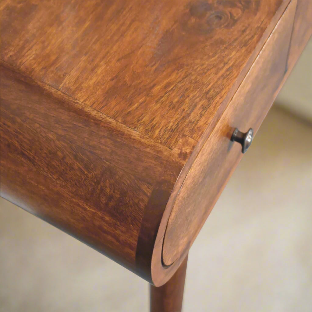 Close view of top left corner of rounded dressing table, with chestnut finish, showcasing the smooth rounded edge and drawer pull handle