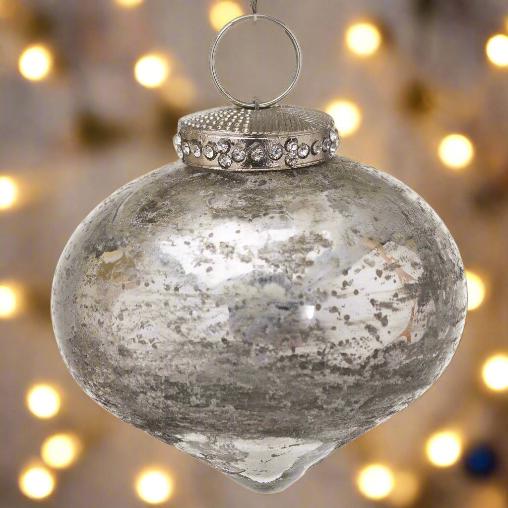 Decorative antique silver tear-shaped Christmas Bauble adorned with a crystal encrusted cap, hanging in a festive fairy light setting.