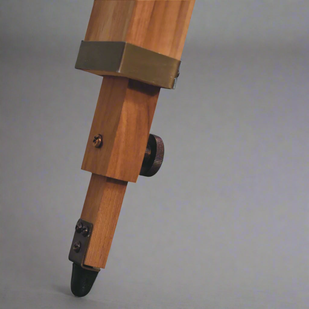 Close-up view of the end of a natural finish tripod leg of the Brass Antique Tripod Fold Spotlight Floor Lamp, showcasing its classic finish.