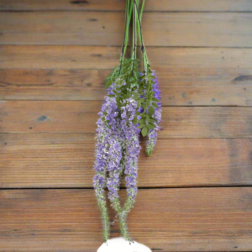 Aerial view of a bunch of purple wisteria sprays on a wooden surface.