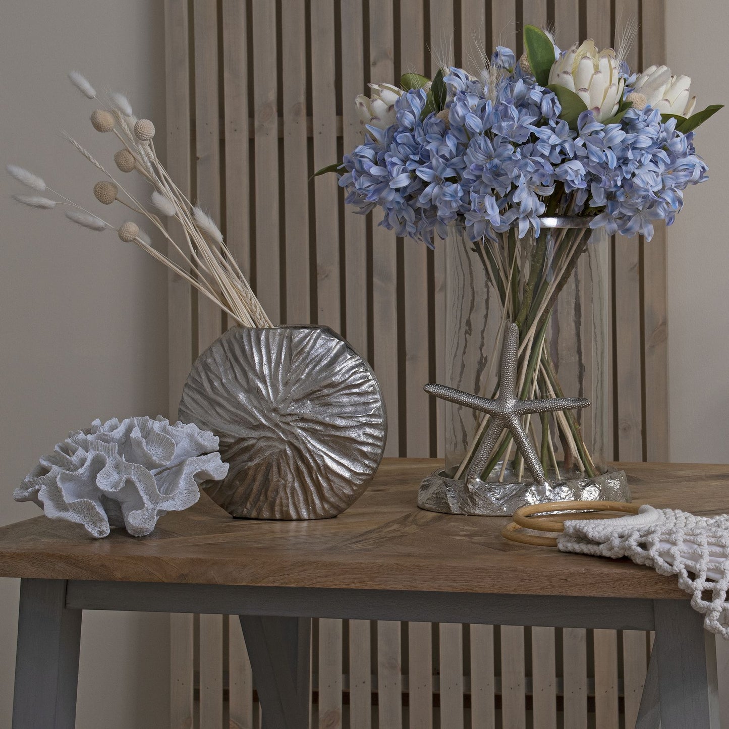 Closer view of a bunch of light blue agapanthus in a clear vase on a table styled with decorative items.