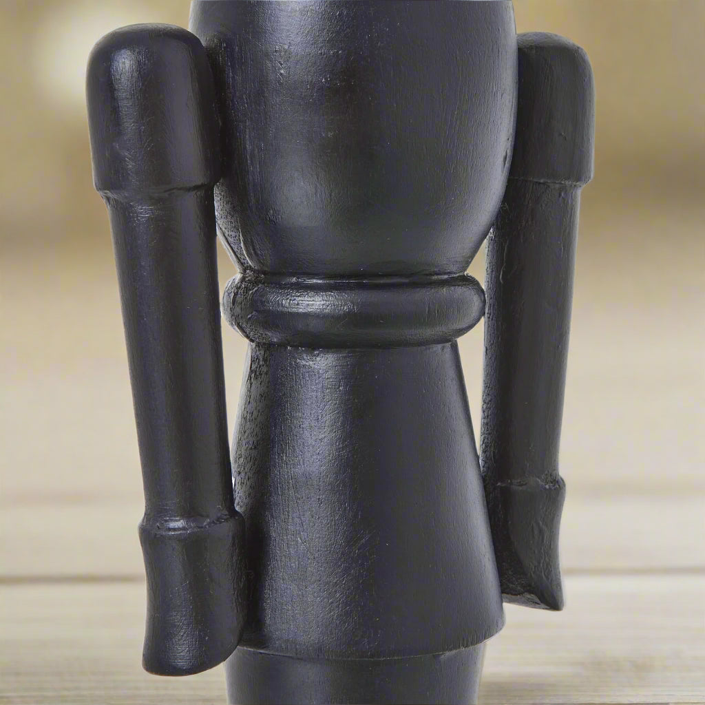 Detailed view of the middle section of a minimalist black wooden nutcracker decoration, highlighting the smooth solid wood construction.