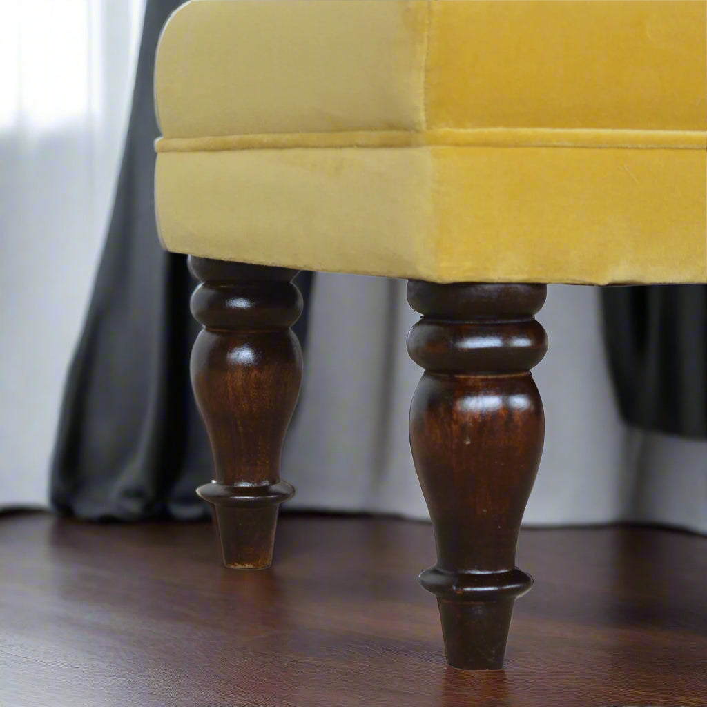Close-up focus on the turned legs of the mustard velvet chaise, highlighting their classic walnut finish.