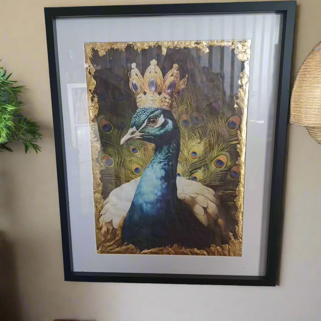 Side-angled view of the Prince Peacock print hanging on a wall in a gold-accented frame.