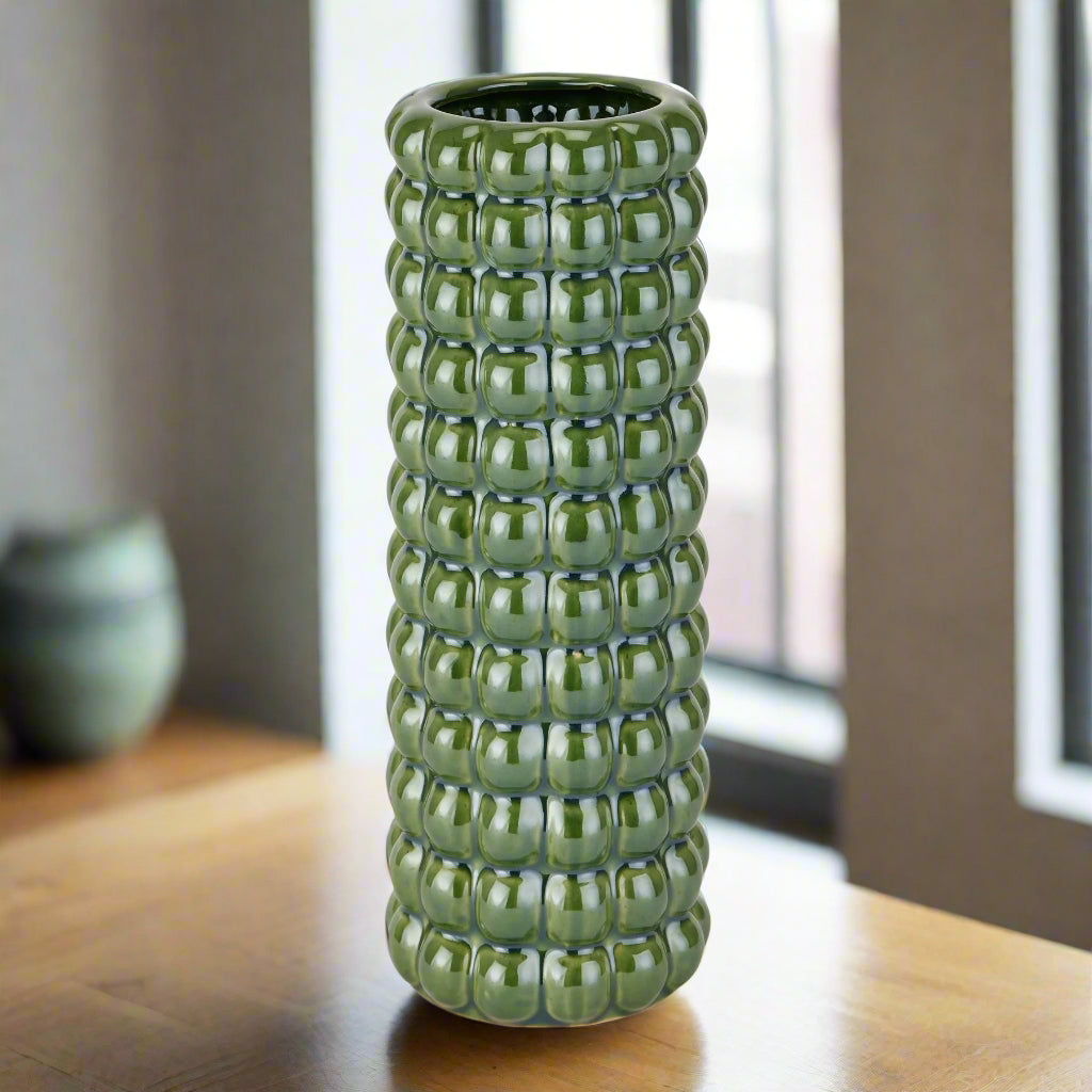 Front view of an upright Seville Olive Bubble Vase on a wooden table.