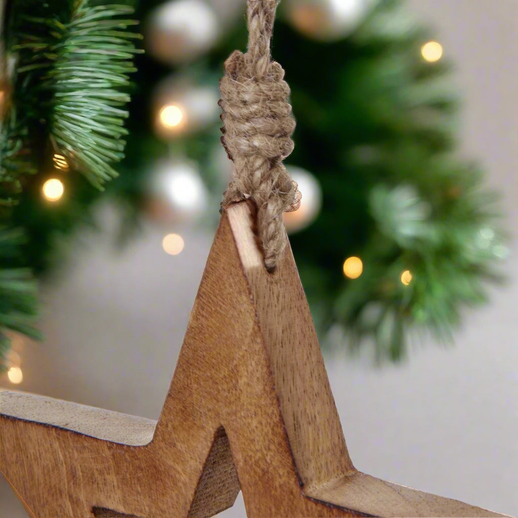 Close up view of a wooden star decoration hanging from. a Christmas tree, showcasing the durable twine.