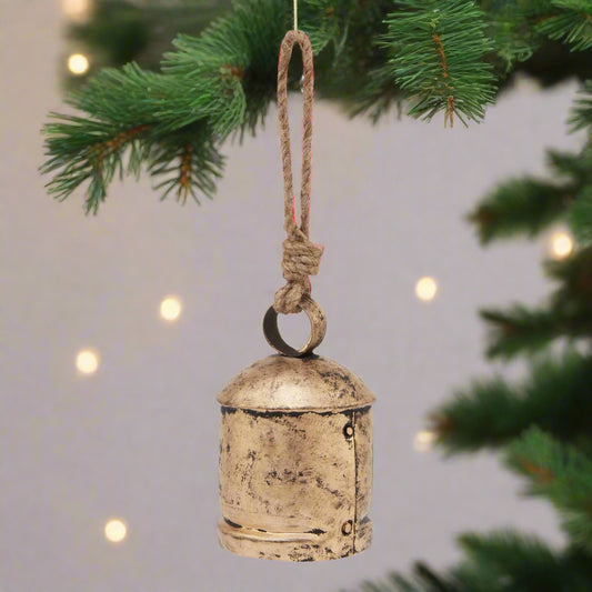 Antique Gold Bell Bauble hanging from a Christmas Tree, close up view.