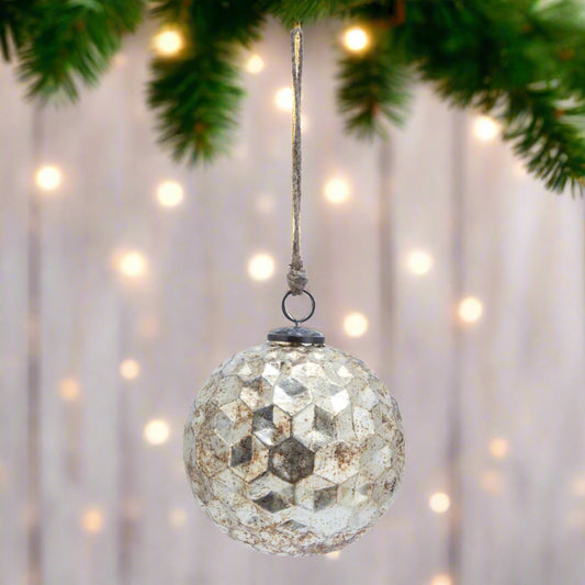 Glass round bauble hanging from Christmas tree showcasing its hexagonal burnished glass texture.