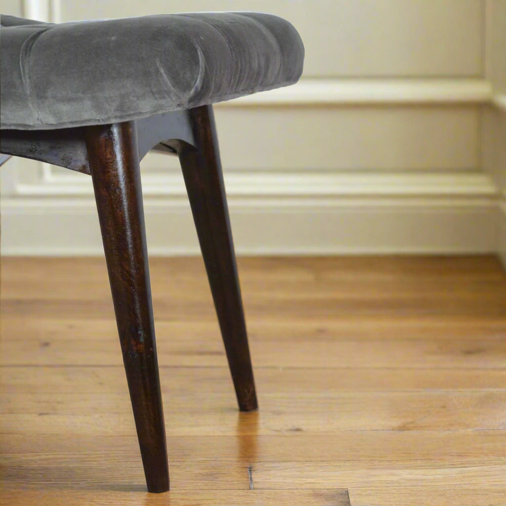 Close-up focus on the Nordic style legs of the grey velvet curve stool, highlighting their design and walnut finish.