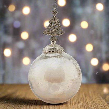 Decorative glass Christmas hanging ornament with an ombre coffee coloured bauble ball and tree-shaped bejewelled top placed on a wooden table with festive background.