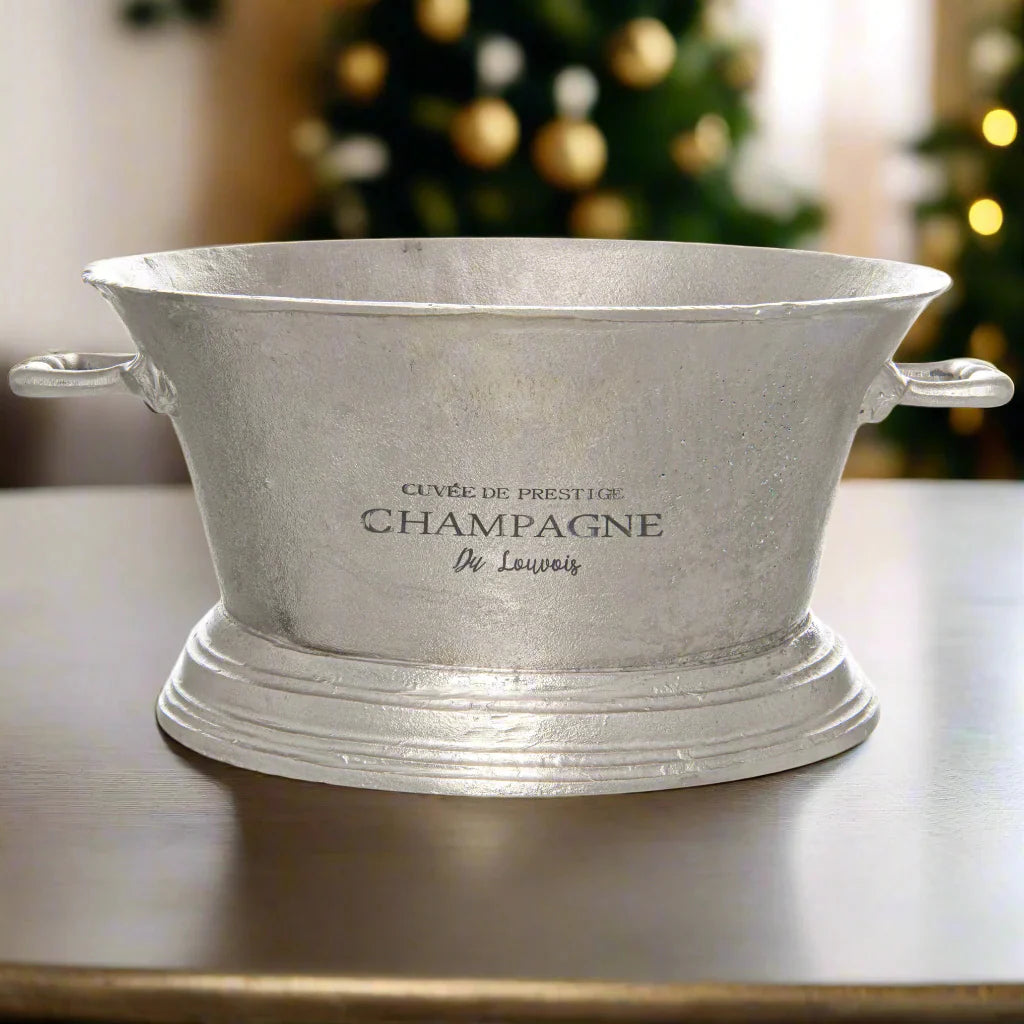 Large silver champagne cooler with 'Cuvée de Prestige Champagne De Louvois' text in a festive setting