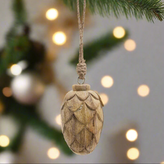 Close up view of wooden pine cone hanging decoration, hanging from a christmas tree by it's twine. Shop now at Purple Flamingo UK.