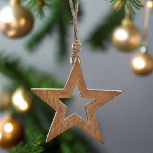 Wooden star hanging decoration showcasing back view of cut-out star shape in middle, star is hanging in a festive scene. Buy at Purple Flamingo UK