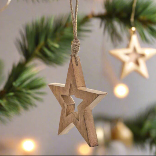 Wooden star hanging decoration showcasing front view of cut-out star shape in middle, star is hanging in a festive scene. Buy at Purple Flamingo UK