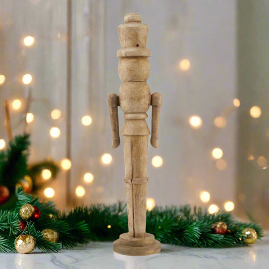 Large wooden nutcracker figure standing proud on a marble fireplace with festive garlands. Shop at Purple Flamingo UK