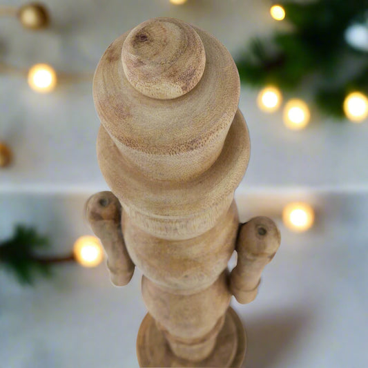 Birds eye view of wooden nutcracker figure displaying the smooth crafted curves of the ornament, setting is festive. Purchase at Purple Flamingo UK.