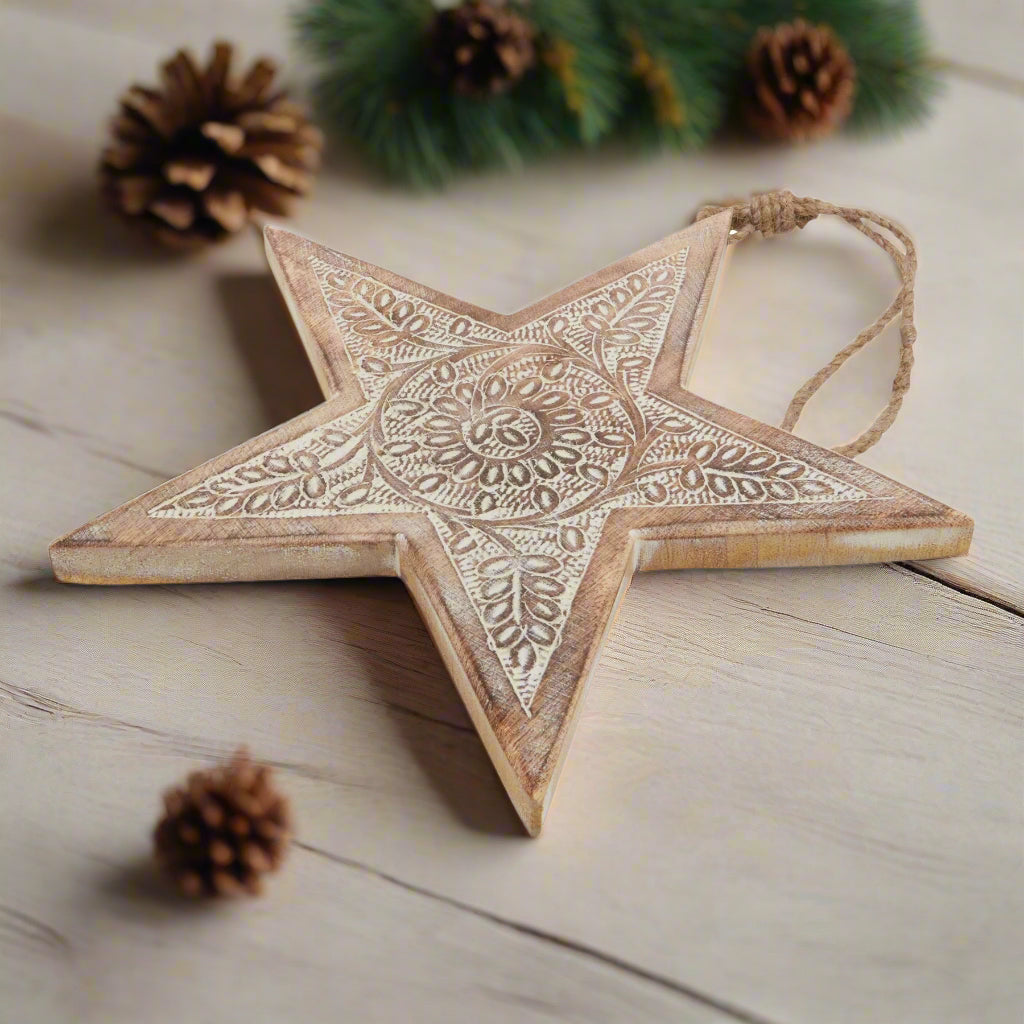 Wooden star hanging decoration placed down on table, showcasing close up of   intricately cut pattern and hanging twine, buy at Purple Flamingo UK