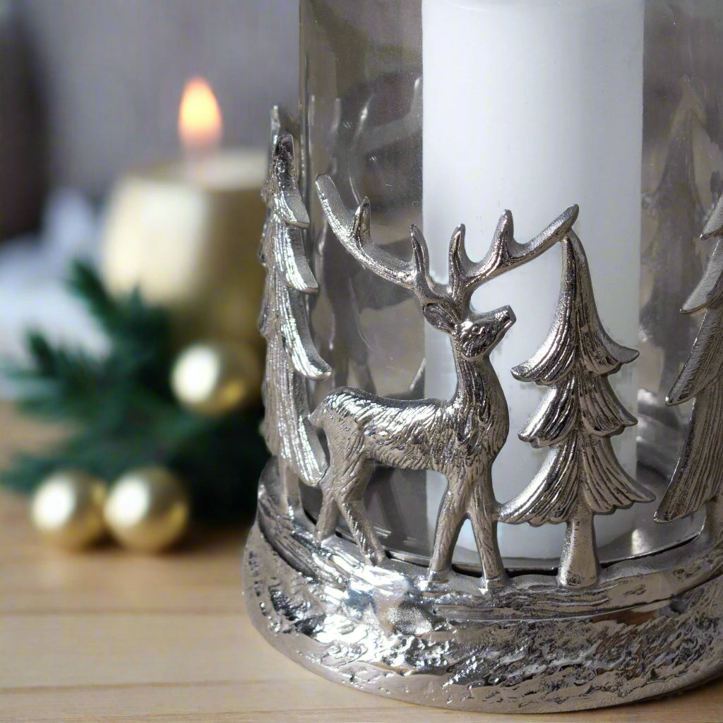close up bottom view of decorative hurricane lantern displaying beautiful metal cut-out design of deer and nordic trees in a festive setting. Purple Flamingo UK.