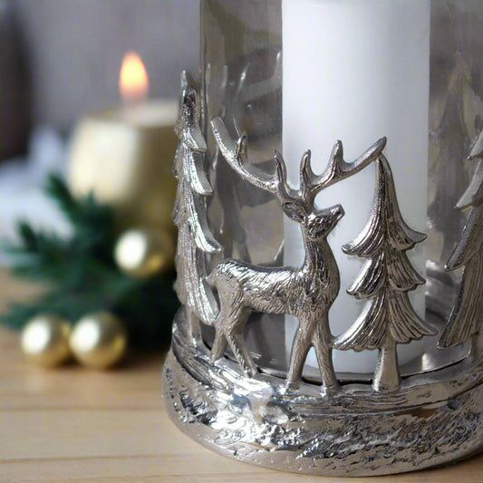 close up bottom view of decorative hurricane lantern displaying beautiful metal cut-out design of deer and nordic trees in a festive setting. Purple Flamingo UK.