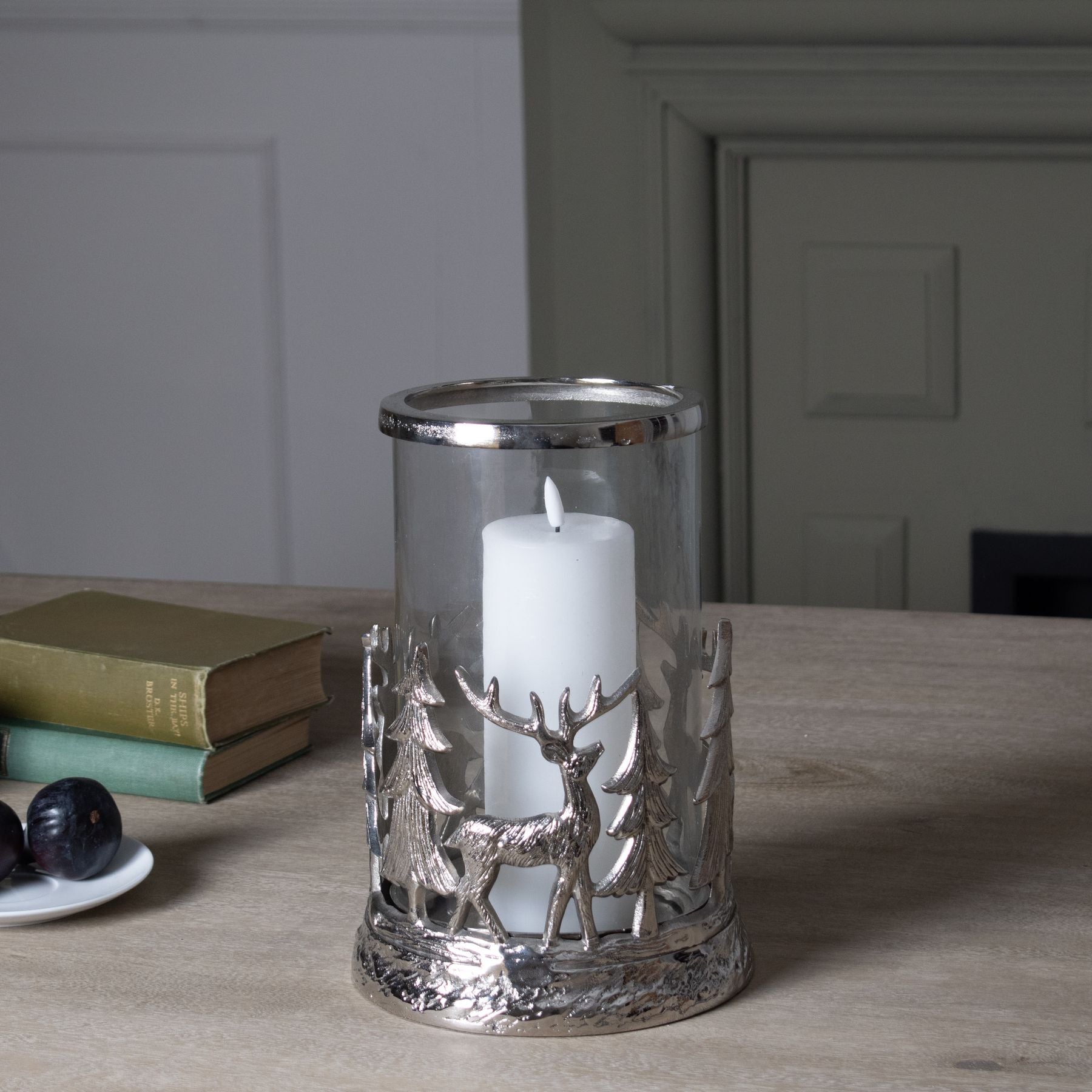 Decorative hurrican lantern with a lit candle, placed on a table in a contemporary living space. Shop at Purple Flamingo UK.
