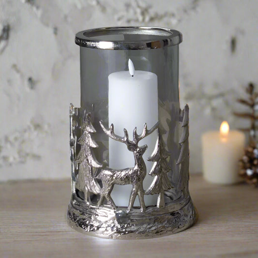 Beautiful decorative candle holder with candle inside, displaying the intricate deer and tree metal design, festive setting. Shop at Purple Flamingo UK