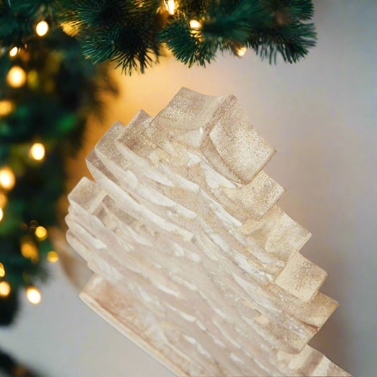 wooden christmas tree standalone decoration with snowy white wash finish placed on a a mantel showing the top view showcasing the tiered detail