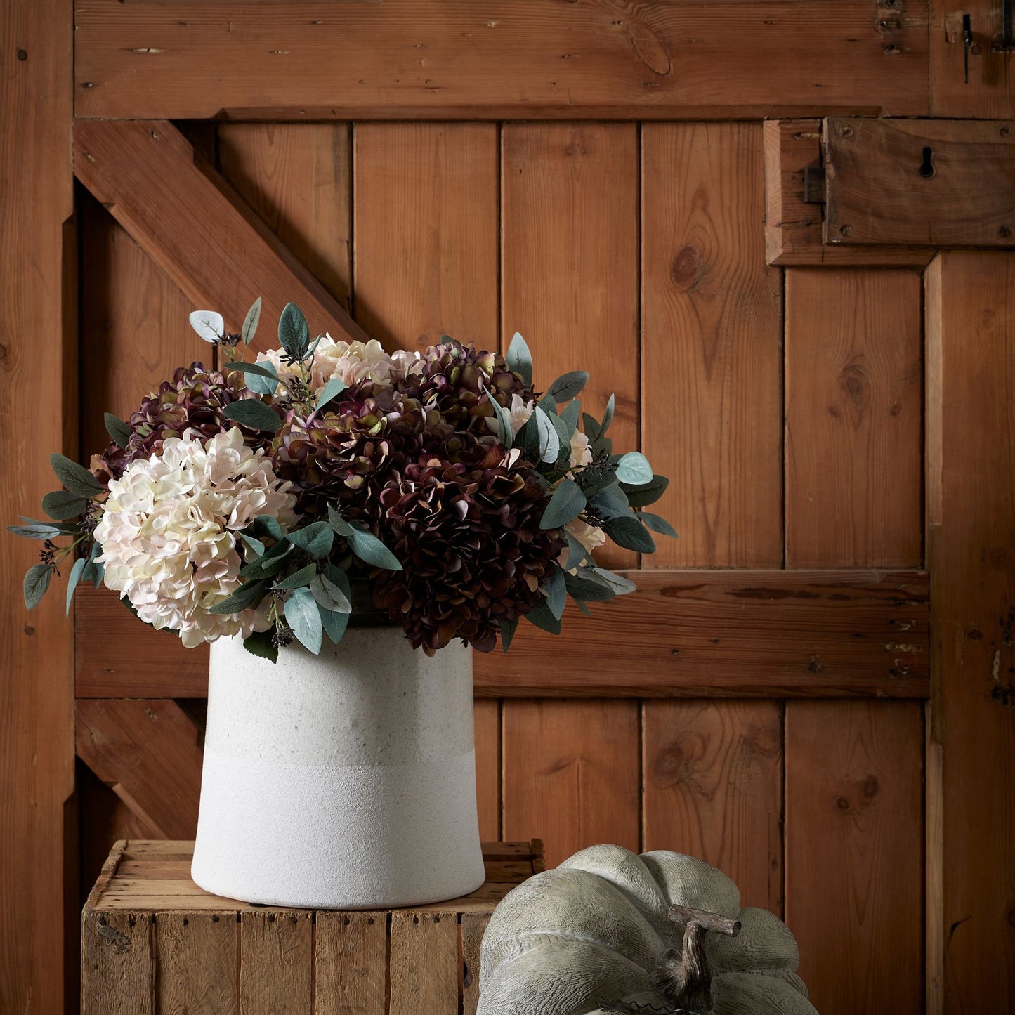 Autumn Coffee Hydrangea stems styled in a white vase on a wooden box, creating a rustic autumn display – perfect artificial flower décor by Purple Flamingo.