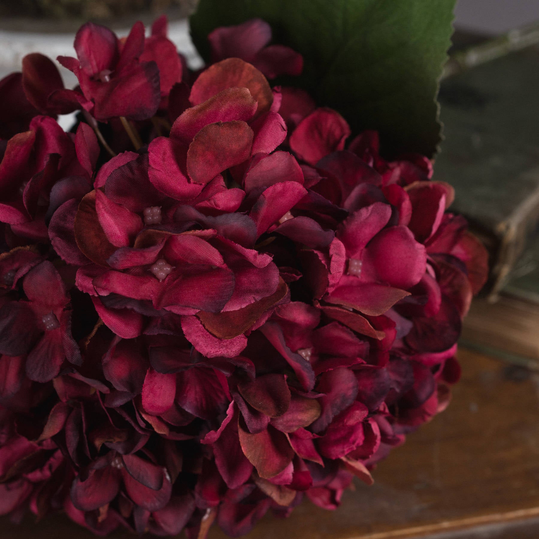 An Autumn Ruby hydrangea bouquet displayed on a wooden surface, showcasing its texture.