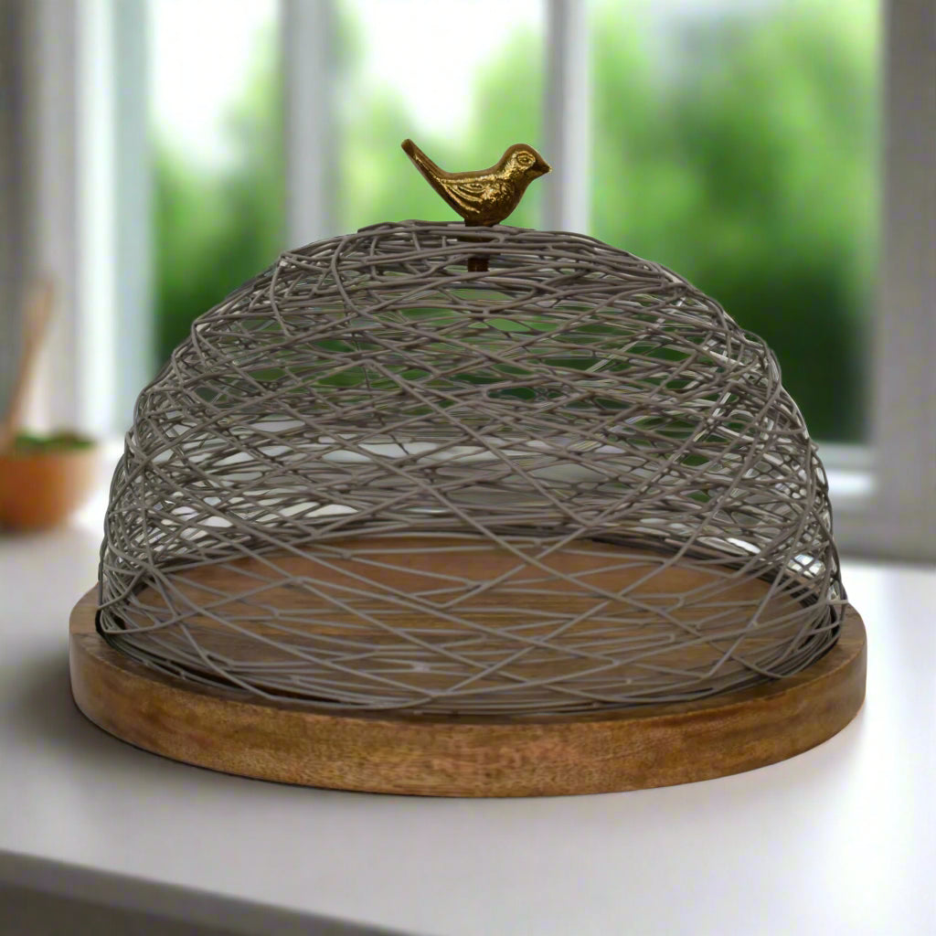 Full front view of the Blue Bird Nest Cake Stand showing its round wooden base and netted top with brass bird handle