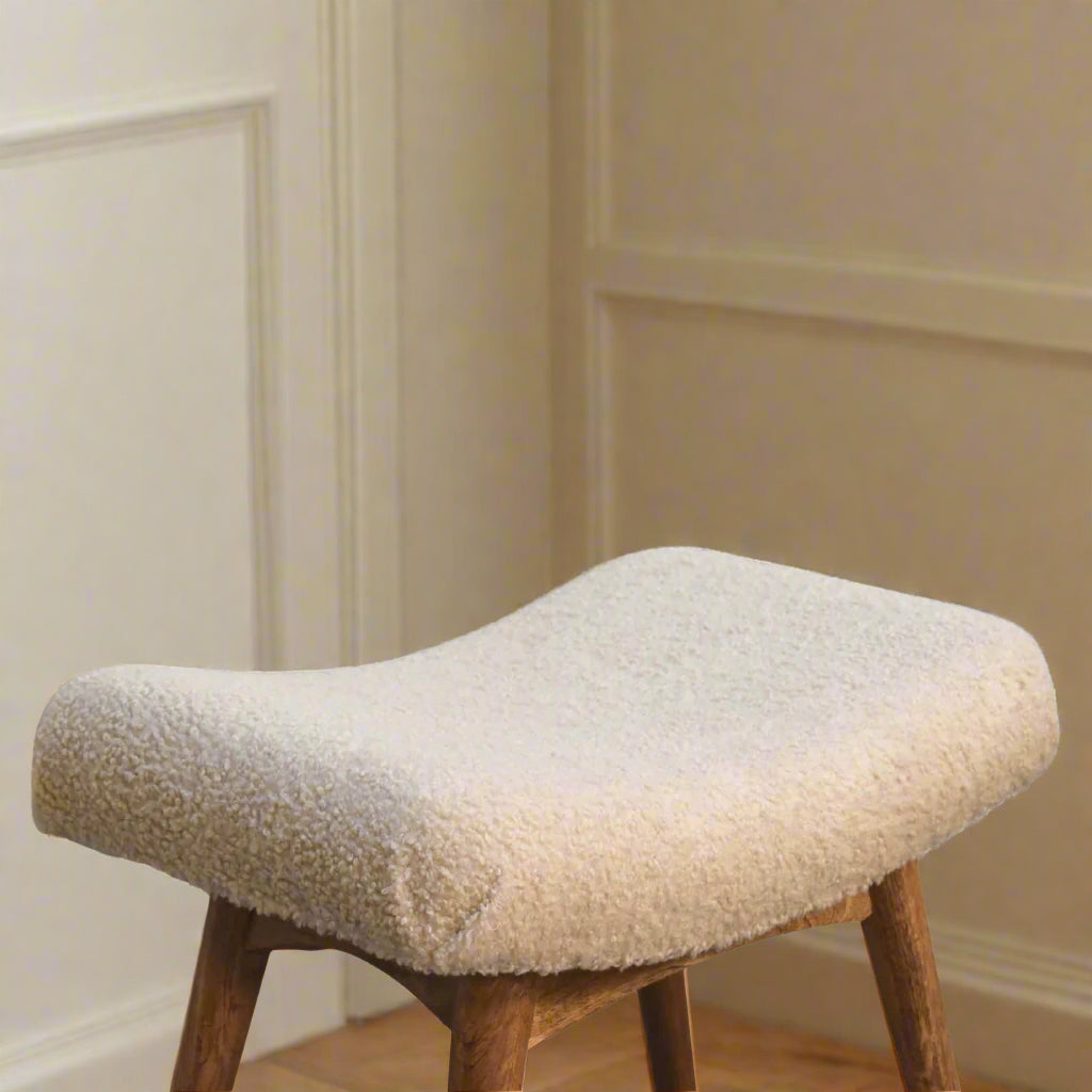 View of the Boucle Cream Curve Stool emphasizing the ergonomic and stylish curve of its cream upholstered seat.