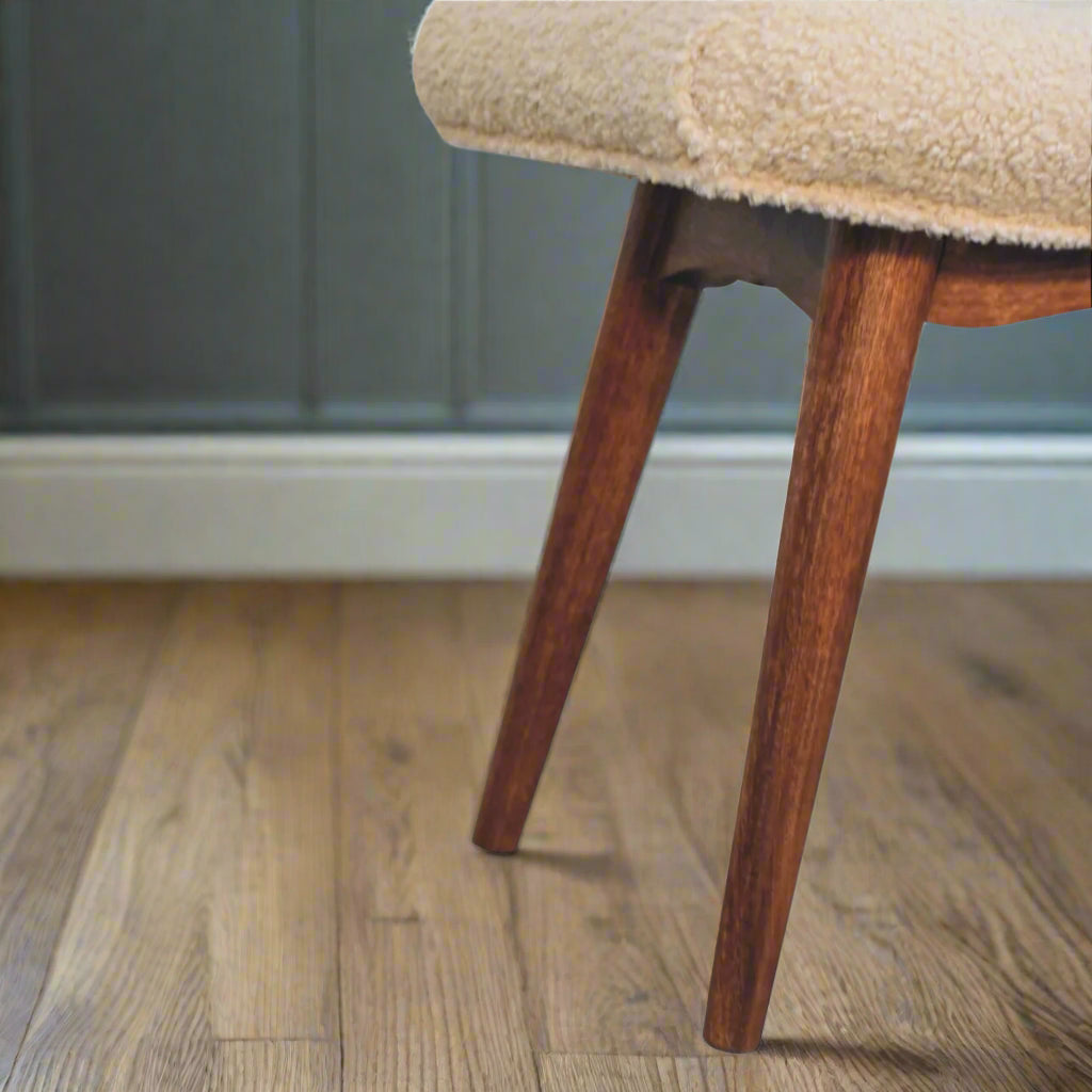 Close view of the Nordic style legs of the Boucle Cream Curve Stool, emphasizing their craftsmanship and honey caramel finish.