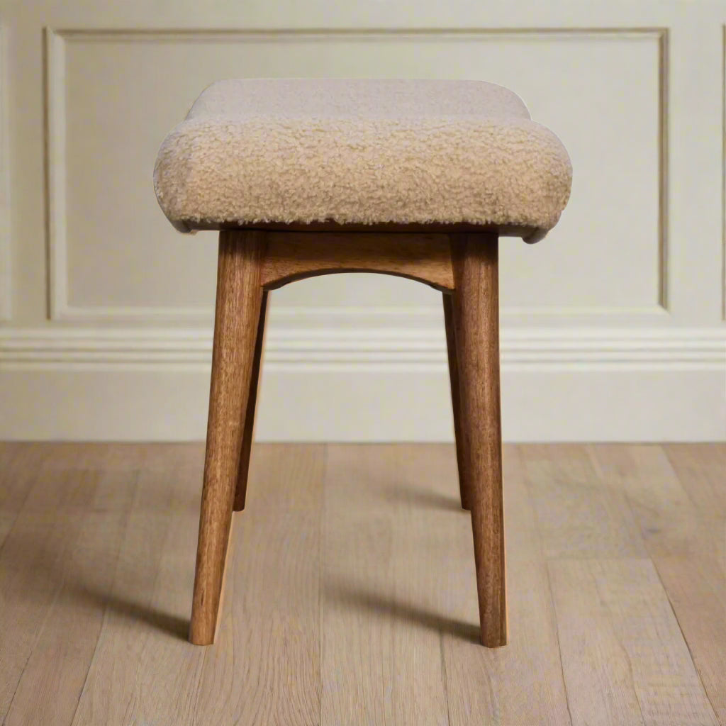 Side view of the Boucle Cream Curve Stool, presenting its full profile and how the curved seat meets the Nordic style legs.