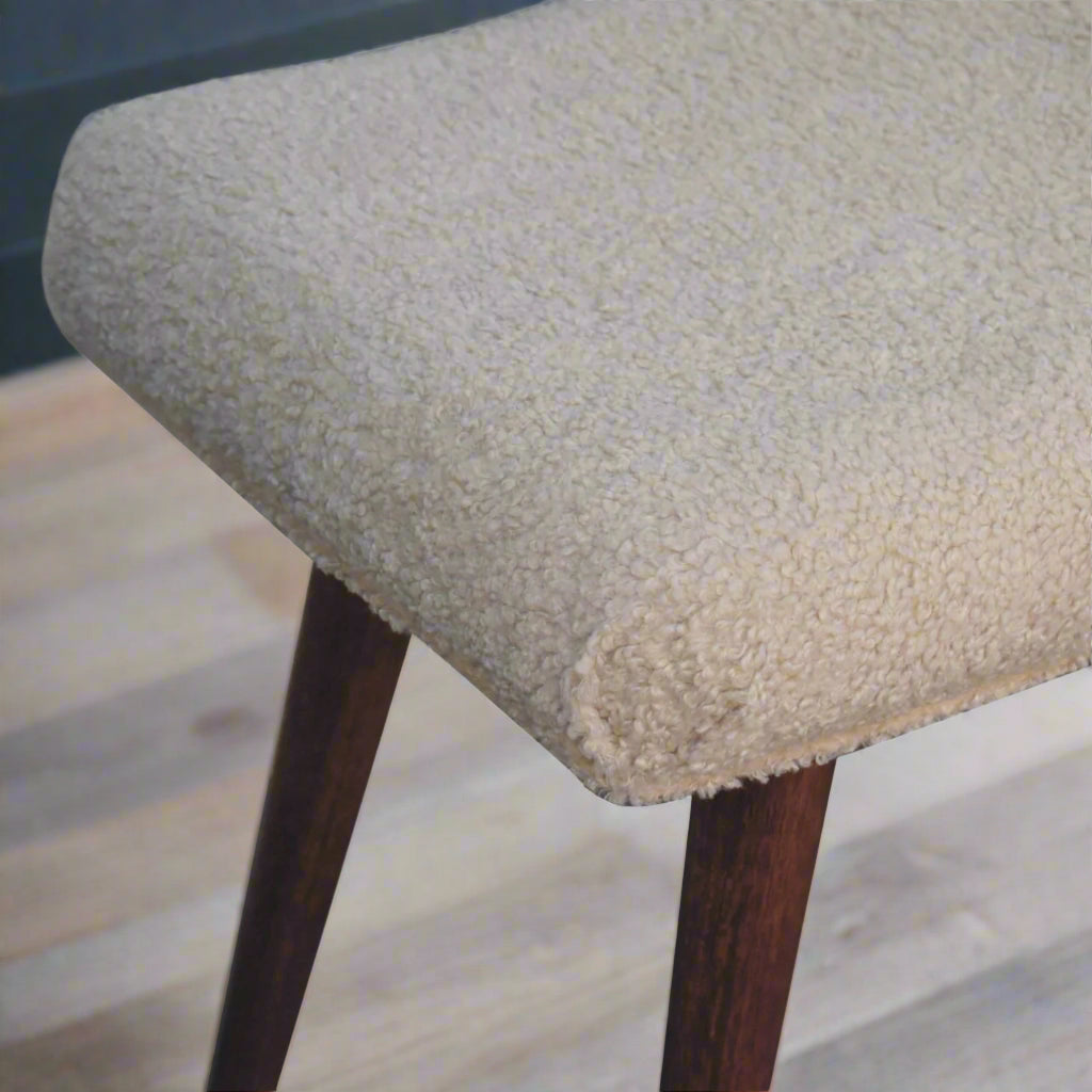 Top-down view of the right edge of the Boucle Cream Curve Stool, showing the boucle fabric and a section of its Nordic style legs.