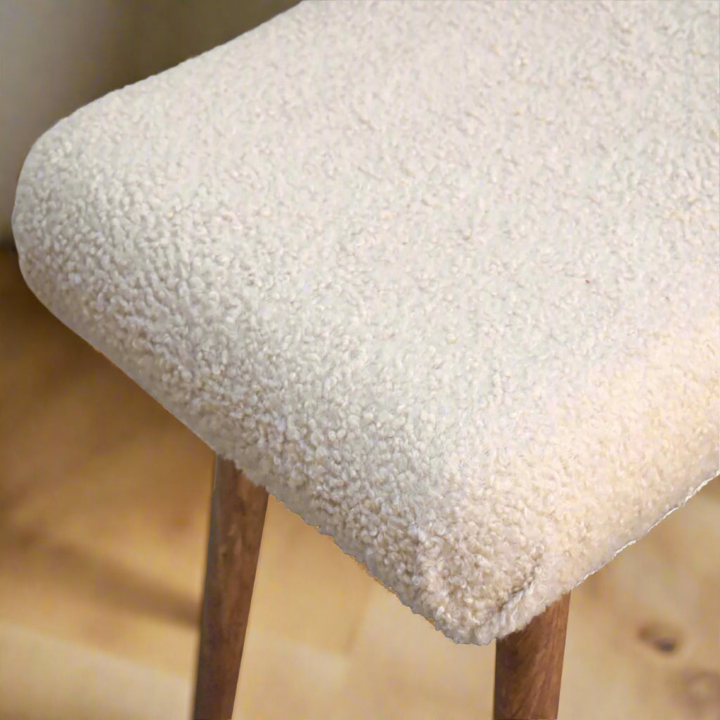 Top-down view of the right edge of the Boucle Cream Curve Stool, highlighting the texture of the handwoven boucle fabric on the seat.