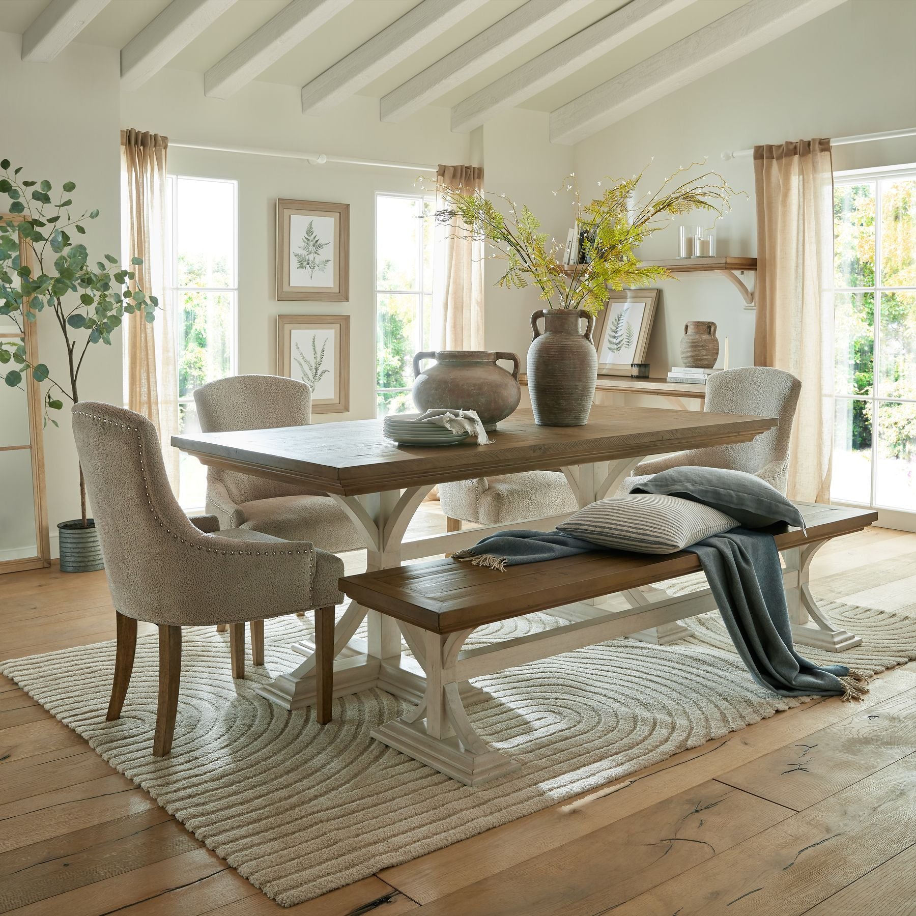 Front view of a room with a bracken fern spray in a vase on a table, surrounded by chairs.

