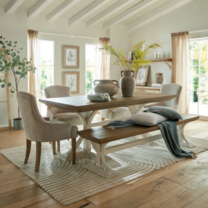 Front view of a room with a bracken fern spray in a vase on a table, surrounded by chairs.

