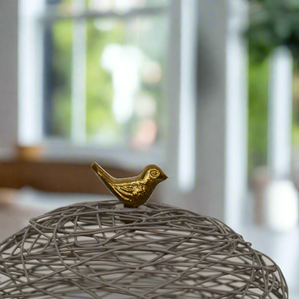 Close-up of the Blue Bird Nest Cake Stand's brass-finished bird handle detail on the netted top
