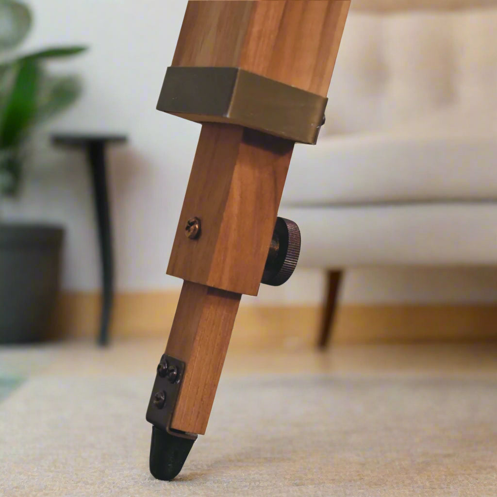 Focused shot on one of the brass-capped legs of the tripod stand of the Brass Caged Spotlight Floor Lamp.