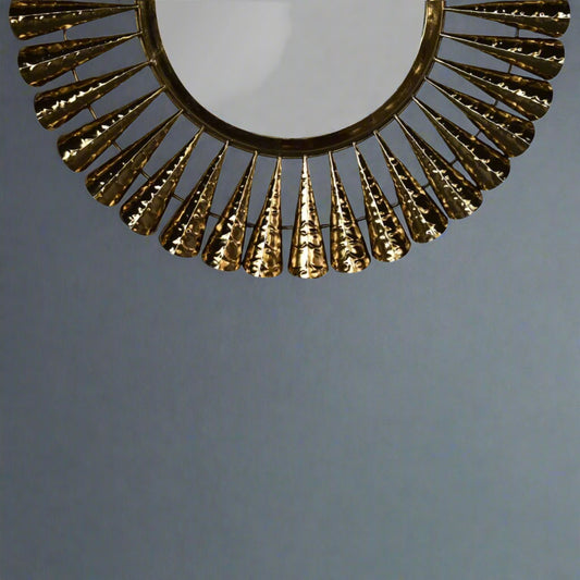 View of the brass coned mirror from a lower than eye level, showing half the mirror and the brass cones around it.