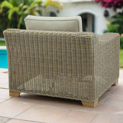 Back view of the Capri Armchair, showing the wicker weave, edge of the backrest Olefin cushion, and the acacia feet.