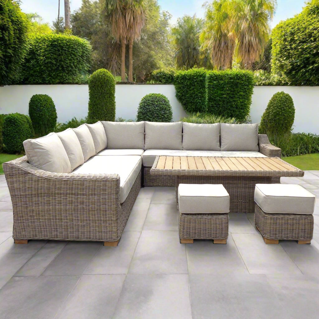 Capri corner sofa set with matching riser table and two stools, styled on a patio with grey wicker frame and plush grey cushions.