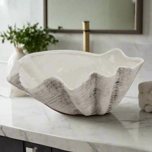 Front view of the large 40cm ceramic Adele Shell bowl on a white tabletop, with an ornamental flower positioned behind it.
