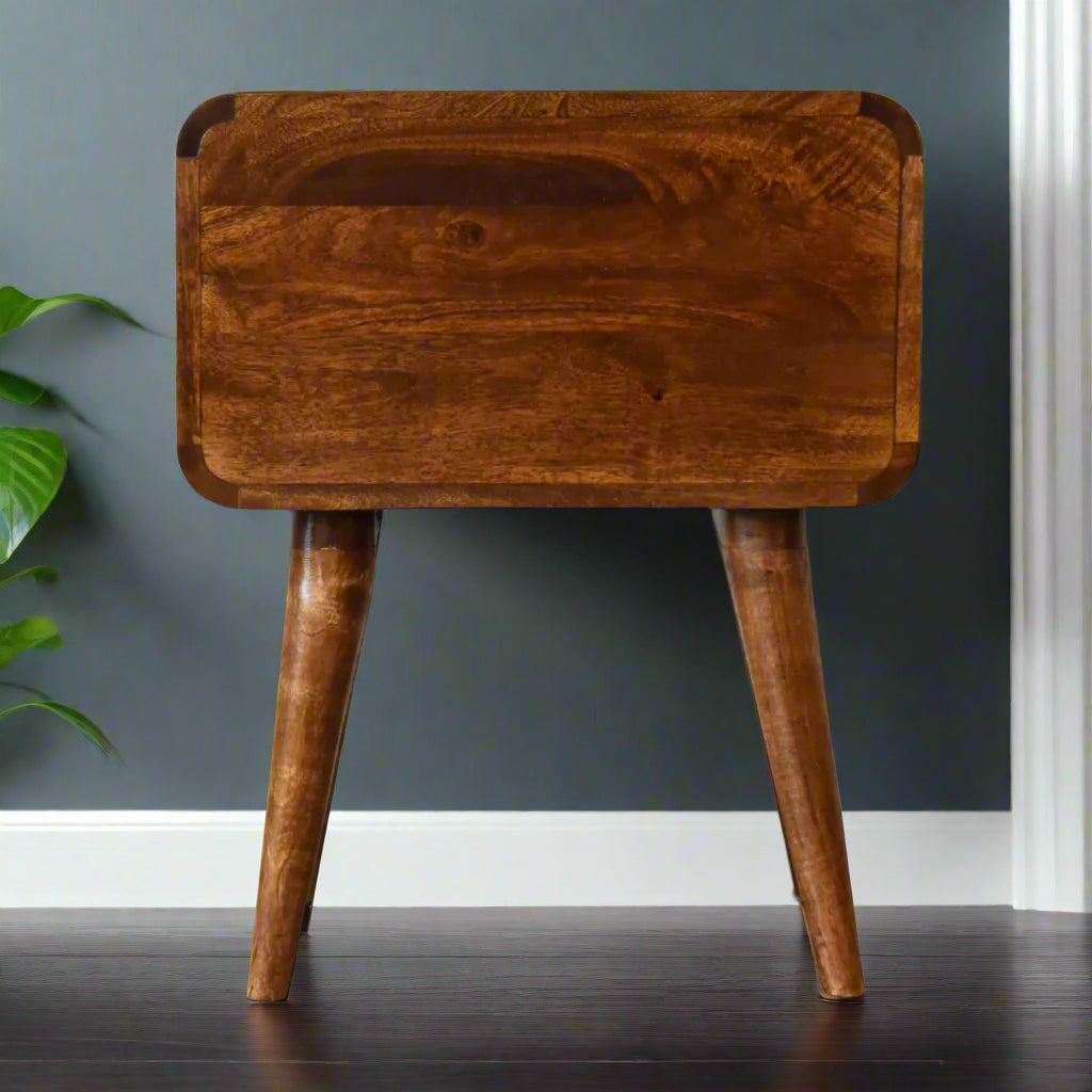 Rear view of the curved 2-drawer bedside table in chestnut finish, showing the solid mango wood construction and tapered Nordic-style legs from behind.