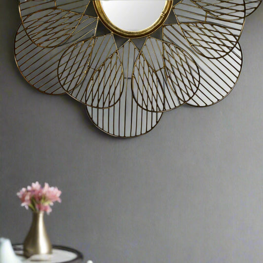 Styled view of gold flower mirror on the wall with floral decor beneath, adding charm to interior space.