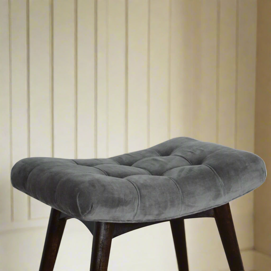 Elevated angled view of the grey velvet curve stool, displaying its comfortable seat and a visible section of its legs.
