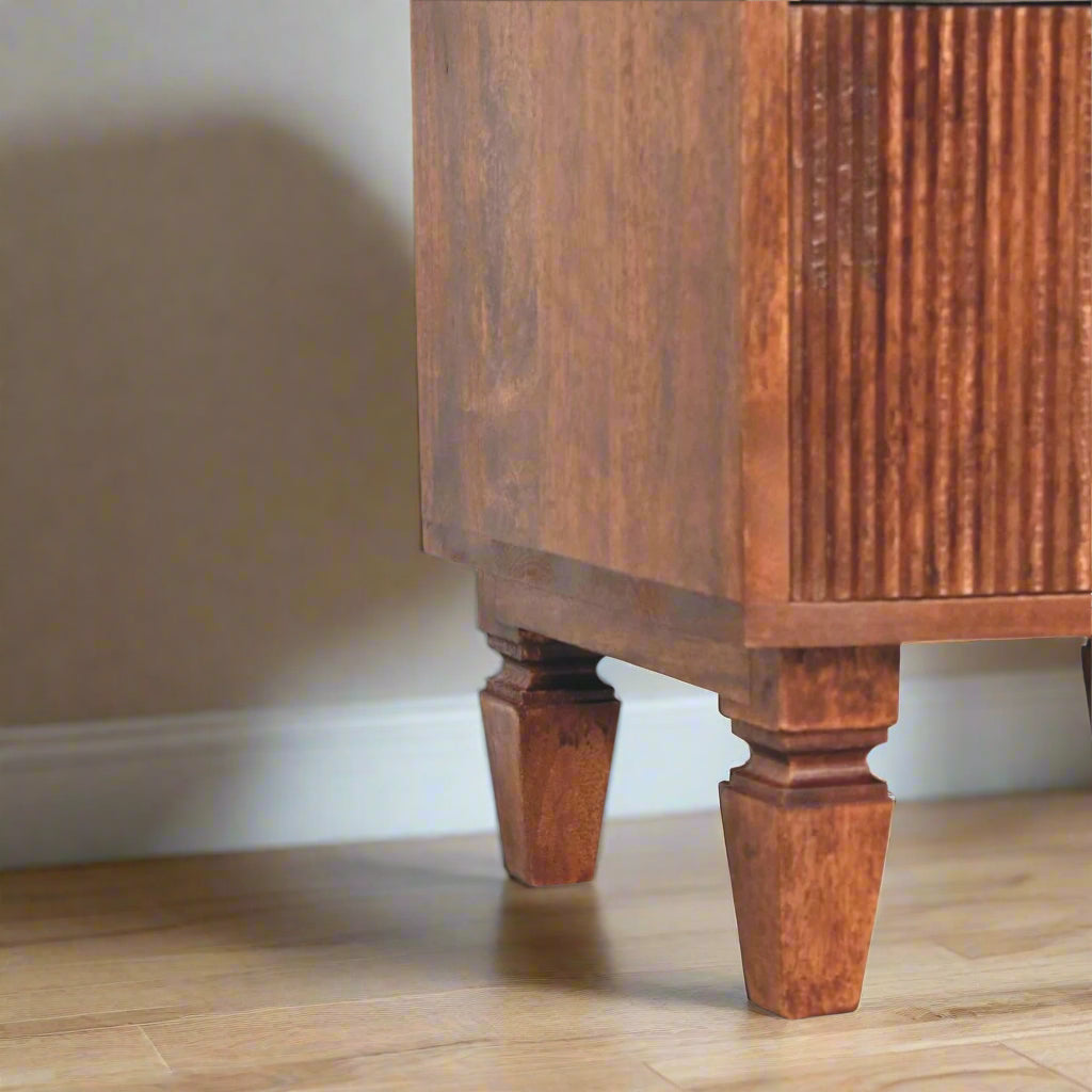 harper bedside table, with amber oak finish displaying close up of right raised carved legs.