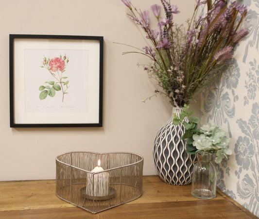 Decorative silver heart candle holder displayed with a bouquet of flowers, ideal for romantic or vintage-inspired home interiors.