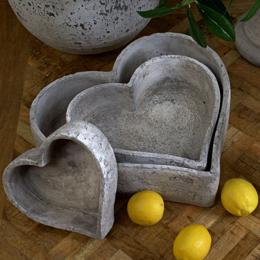 Set of three graduated heart-shaped ceramic dishes with a rustic stone finish, styled with lemons and greenery for a fresh decor look.
